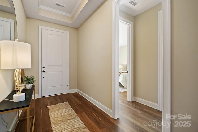 foyer entrance featuring visible vents, dark wood-type flooring, and a tray ceiling