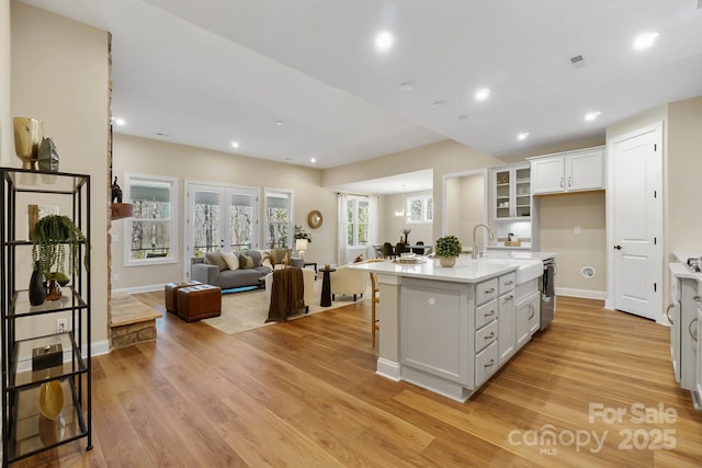 kitchen with light wood-style flooring, a sink, light countertops, white cabinetry, and open floor plan