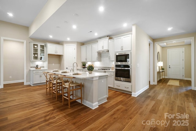 kitchen with tasteful backsplash, stainless steel appliances, light countertops, and wood finished floors