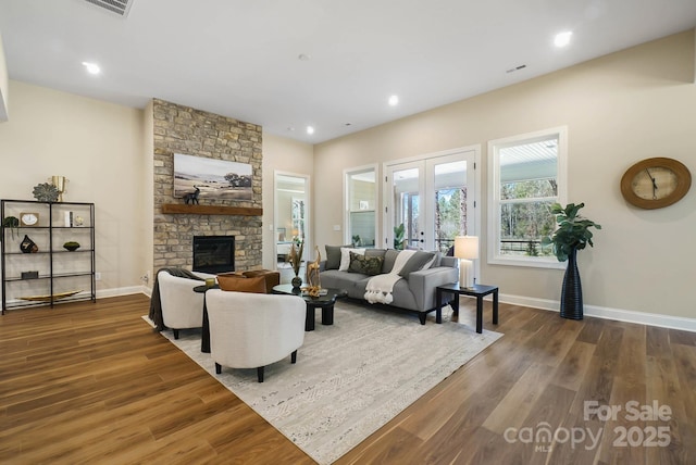 living area with french doors, a fireplace, baseboards, and wood finished floors