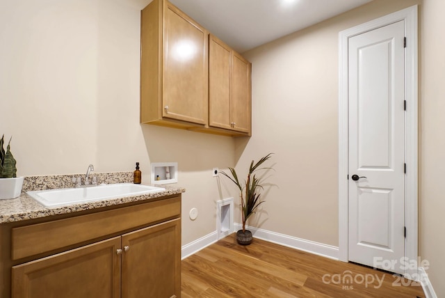 washroom featuring hookup for a washing machine, baseboards, cabinet space, a sink, and light wood-style floors