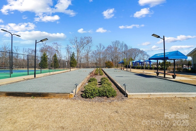 view of community with a tennis court and fence