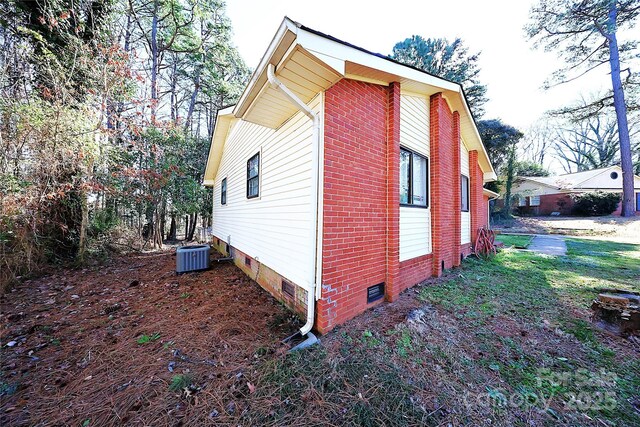 view of side of property with crawl space, central air condition unit, and brick siding