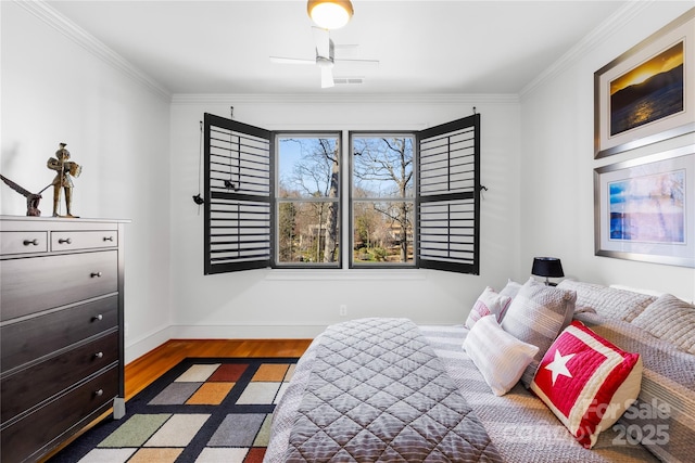 bedroom with visible vents, ornamental molding, baseboards, and wood finished floors