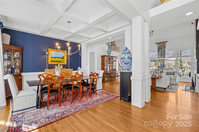 dining room featuring beam ceiling, coffered ceiling, wood finished floors, an inviting chandelier, and wainscoting