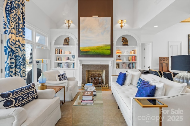 living room featuring built in features, a fireplace, and a towering ceiling