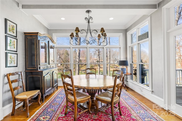 dining room with a chandelier, a healthy amount of sunlight, light wood-type flooring, and ornamental molding