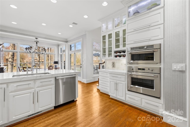 kitchen featuring light wood-type flooring, visible vents, a sink, white cabinetry, and stainless steel appliances