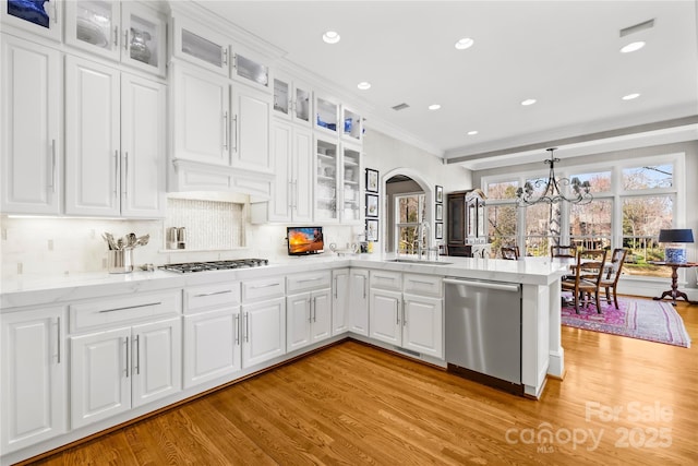 kitchen with dishwasher, a peninsula, light wood-style floors, gas stovetop, and a sink