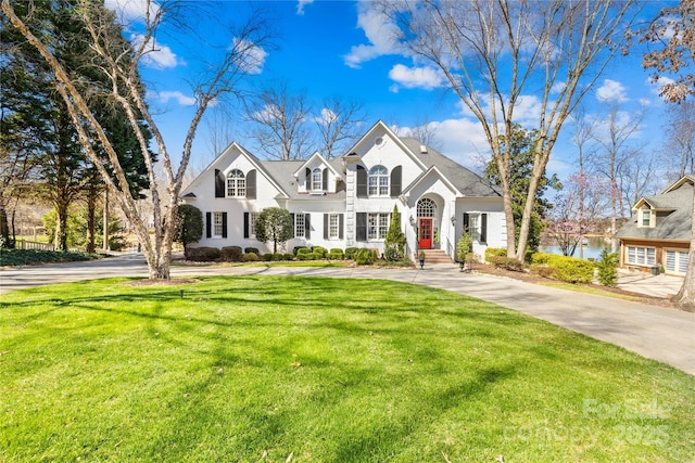 french country inspired facade with a front lawn and a water view