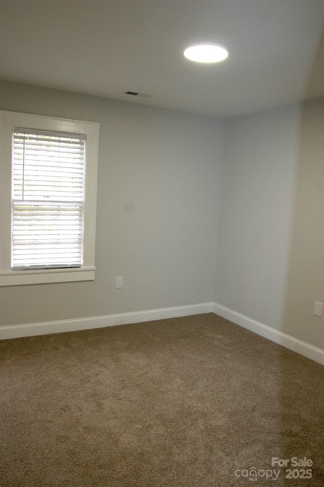 carpeted spare room featuring visible vents and baseboards