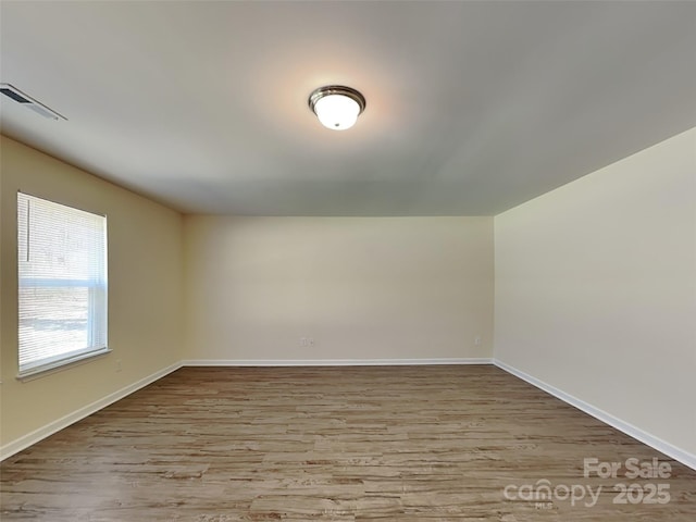 empty room with visible vents, baseboards, and wood finished floors