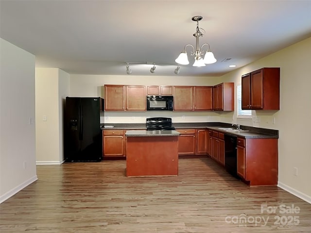 kitchen with dark countertops, a chandelier, light wood-style floors, black appliances, and a sink