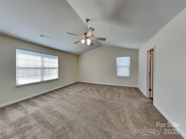 carpeted empty room featuring a wealth of natural light, baseboards, a ceiling fan, and vaulted ceiling