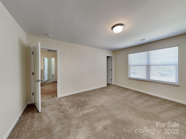 carpeted spare room featuring visible vents and baseboards