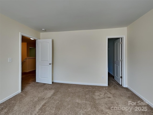 unfurnished bedroom featuring a spacious closet, carpet flooring, and baseboards