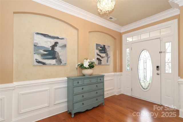 foyer entrance featuring visible vents, a notable chandelier, dark wood-style flooring, and crown molding