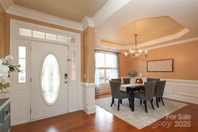 foyer with a tray ceiling, a wainscoted wall, and wood finished floors