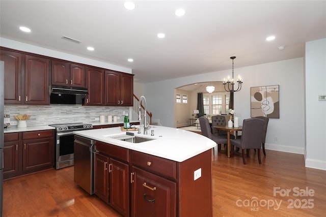 kitchen featuring light countertops, stainless steel range with electric stovetop, ventilation hood, and a sink