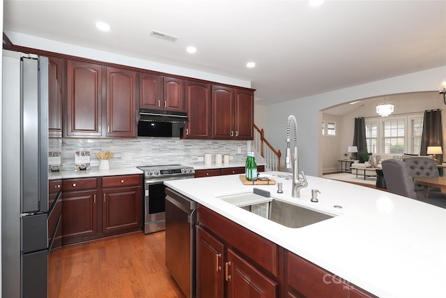 kitchen featuring a sink, extractor fan, light countertops, appliances with stainless steel finishes, and reddish brown cabinets