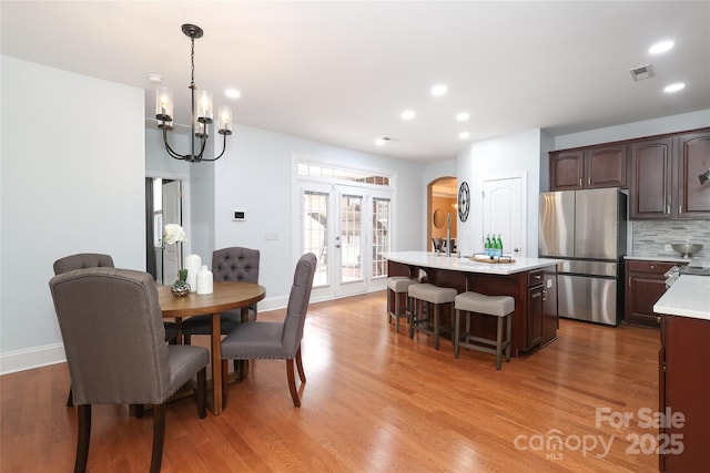 dining area with visible vents, light wood finished floors, recessed lighting, arched walkways, and french doors