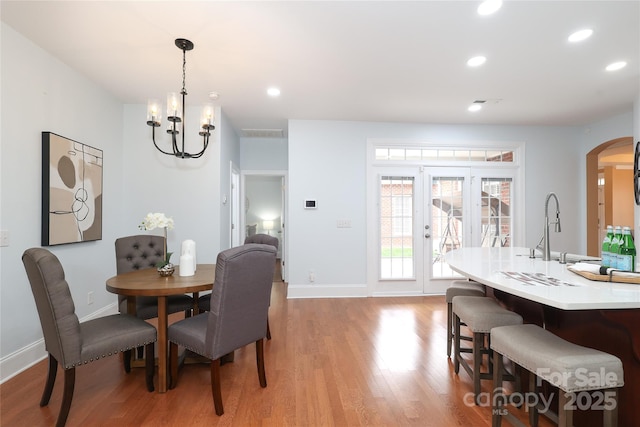 dining space featuring recessed lighting, light wood-style floors, arched walkways, and baseboards