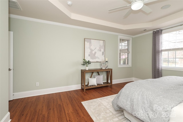 bedroom featuring baseboards, a raised ceiling, visible vents, and wood finished floors