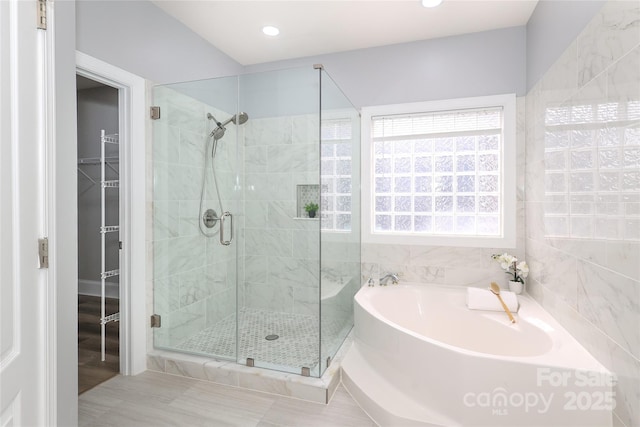 full bath with recessed lighting, a garden tub, a stall shower, and a spacious closet