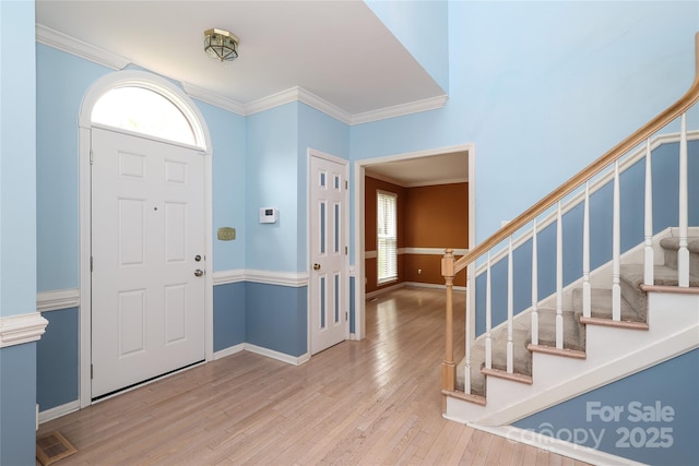 foyer entrance featuring stairs, crown molding, wood finished floors, and visible vents