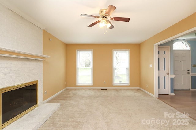 unfurnished living room with ceiling fan, a fireplace, baseboards, and carpet floors