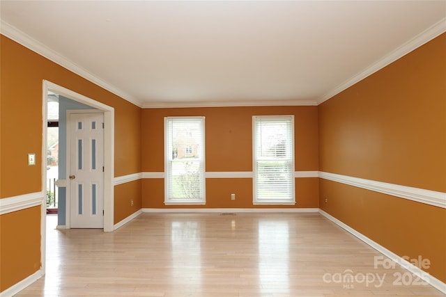 spare room featuring baseboards, light wood-style floors, and crown molding