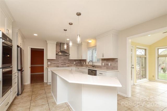 kitchen featuring light countertops, wall chimney range hood, backsplash, and appliances with stainless steel finishes