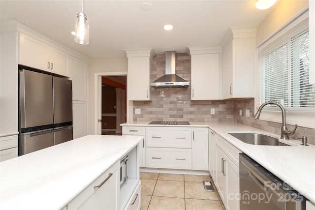 kitchen featuring tasteful backsplash, wall chimney range hood, light countertops, appliances with stainless steel finishes, and a sink