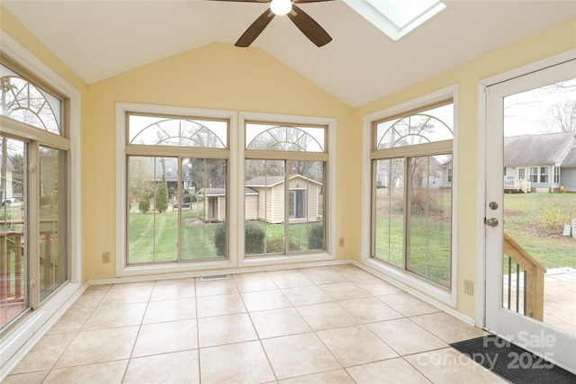 unfurnished sunroom with a wealth of natural light, visible vents, vaulted ceiling with skylight, and ceiling fan