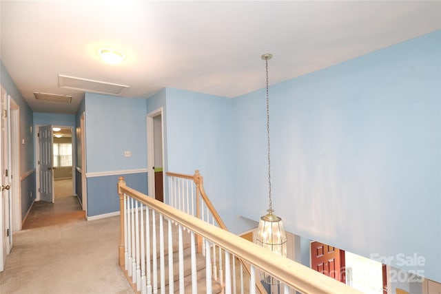 corridor with attic access, an upstairs landing, light colored carpet, and baseboards