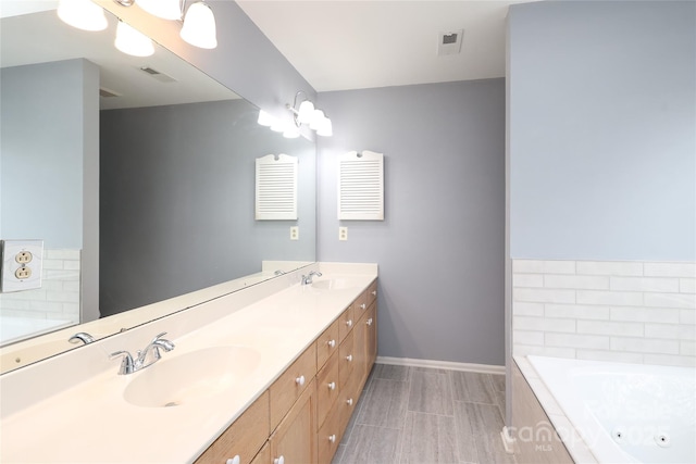 full bath with a sink, visible vents, and a whirlpool tub