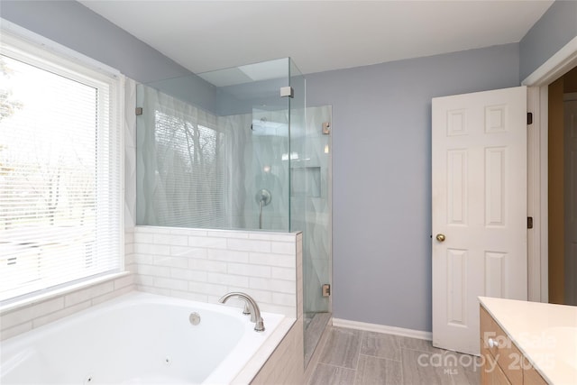 bathroom featuring vanity, a shower stall, a tub with jets, and a wealth of natural light