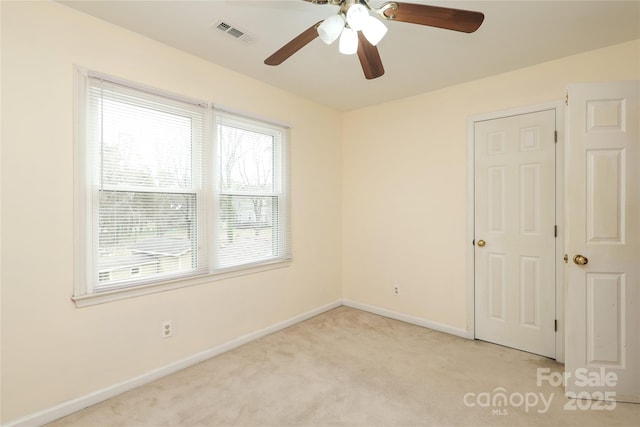 empty room with baseboards, light carpet, visible vents, and ceiling fan