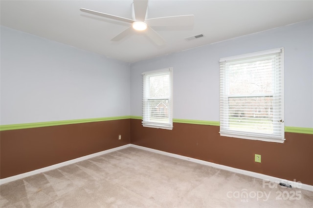 empty room featuring carpet flooring, baseboards, visible vents, and ceiling fan