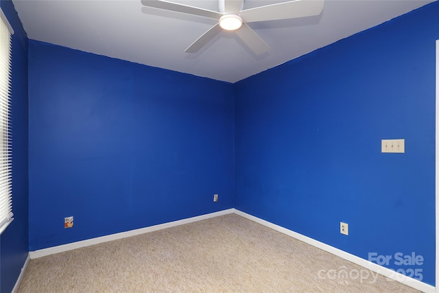 carpeted spare room with a ceiling fan and baseboards