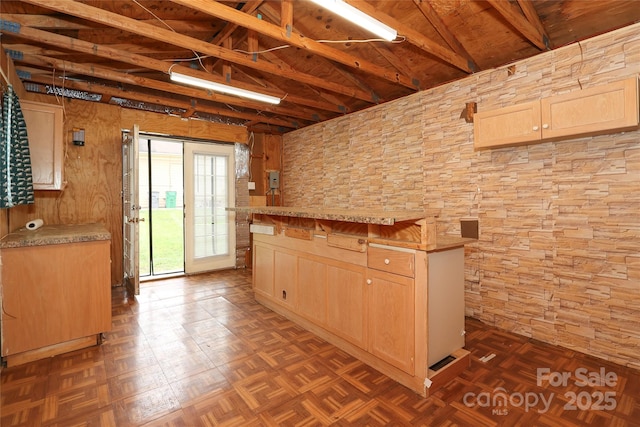 kitchen featuring light brown cabinets, light countertops, and vaulted ceiling