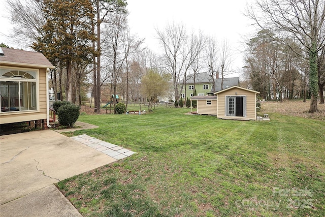 view of yard featuring a playground, an outbuilding, and fence