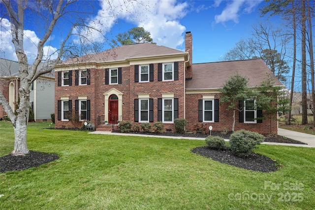 view of front of home with crawl space, a chimney, brick siding, and a front yard