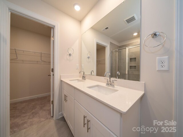 bathroom with a shower stall, a spacious closet, visible vents, and a sink