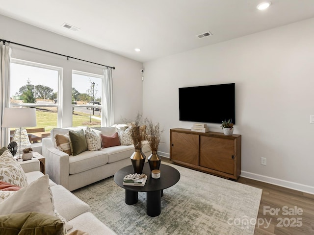 living area featuring visible vents, baseboards, and wood finished floors