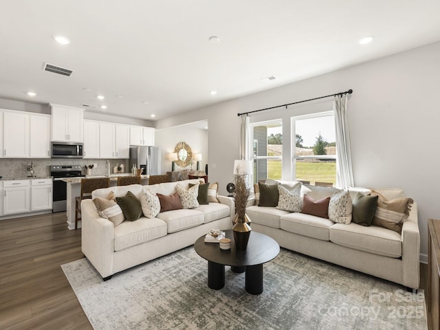 living room with dark wood-style floors, visible vents, and recessed lighting