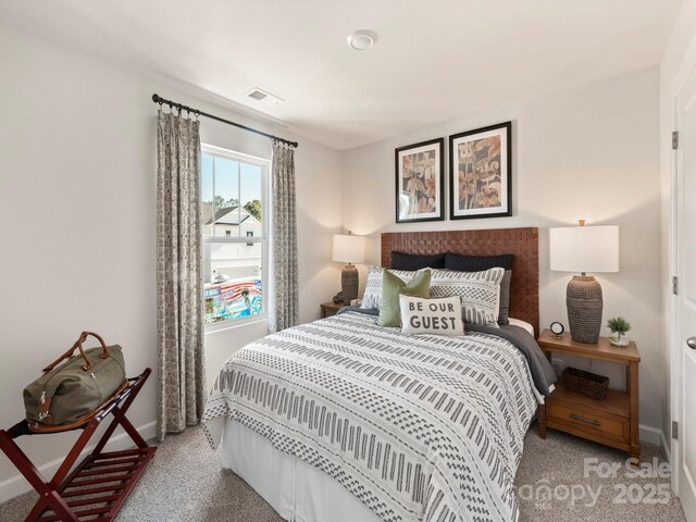 bedroom with visible vents, light carpet, and baseboards