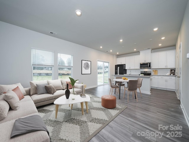 living room featuring recessed lighting, visible vents, baseboards, and light wood-style flooring