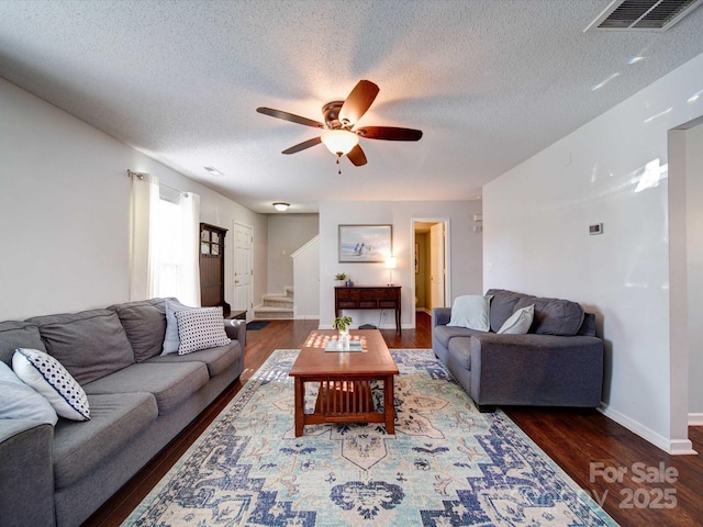 living area with visible vents, a textured ceiling, wood finished floors, and stairway