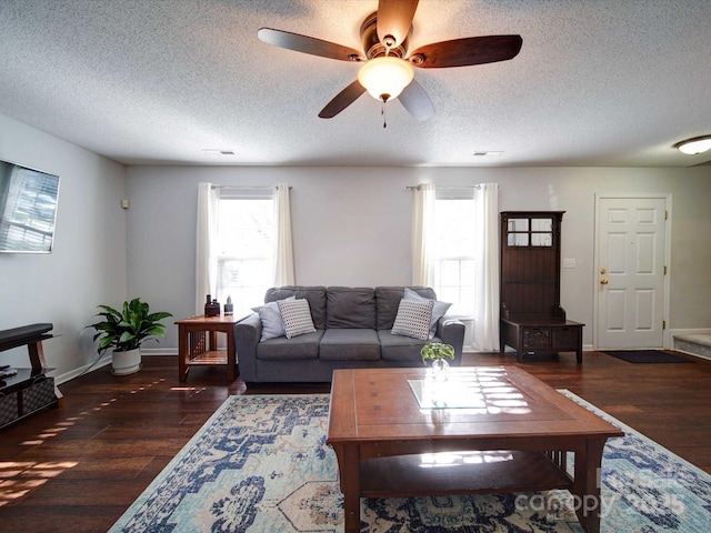 living room featuring a textured ceiling, wood finished floors, baseboards, and ceiling fan